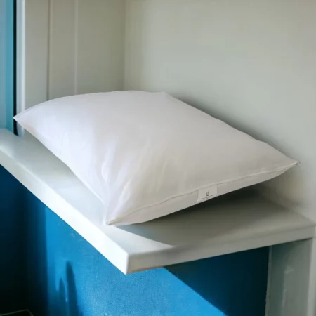 Taie d'oreiller blanche en polypropylène de Litex posée sur une étagère avec fond bleu