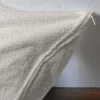 Gros plan sur la fermeture éclair d'une taie d'oreiller en tissu texturé de Litex, évoquant qualité et facilité d'entretien.