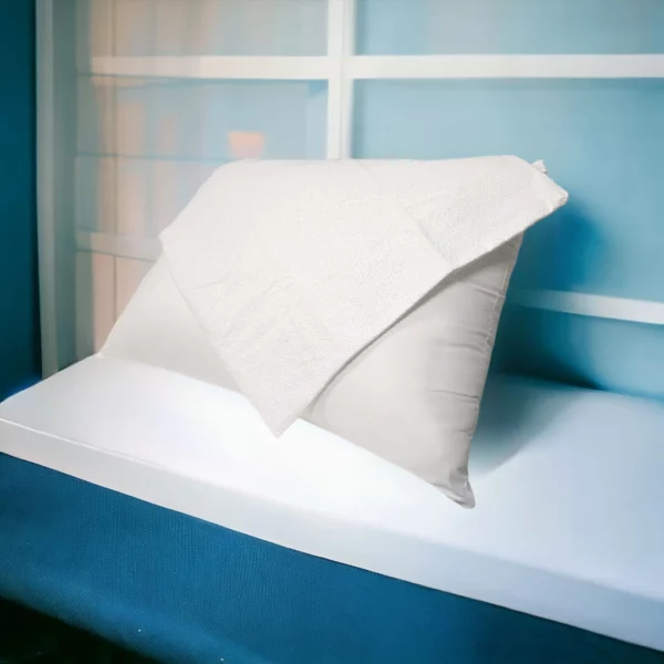 Oreiller confortable avec taie en coton imperméable de Litex, disposé sur une banquette blanche devant une fenêtre.