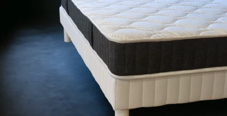 Un matelas d'hôtel de luxe avec sommier tapissier élégant sur fond sombre, représentant le confort haut de gamme.