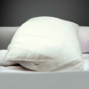 Un oreiller blanc posé sur un lit.
