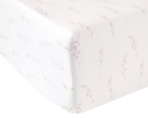 Drap housse blanc orné de délicats motifs floraux roses, confectionné en percale de coton bio, sur un lit.