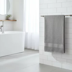 Drap de douche Naïade Gris 70x140 suspendu à une barre, montrant le motif nid d'abeille et sa légèreté.