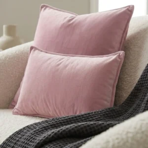 Duo de coussins déco en velours lilas Glamour sur canapé bouclé blanc avec plaid gaufré anthracite.