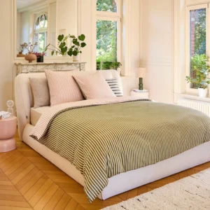 Housse de couette haut de gamme Baudouin Anne de Solène disposée sur un grand lit dans un appartement lumineux avec parquet.