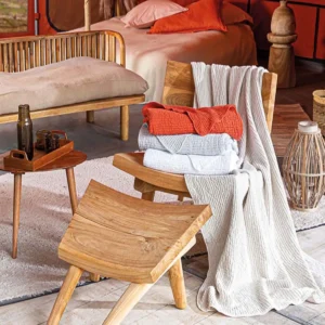 Plaid réversible Jaipur Toison d'Or coloris terracotta plié sur un fauteuil en bois